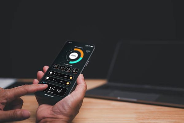 Individuals monitoring home electricity usage with mobile apps, Smart Home Control Interface, User interacts with smartphone app to manage home automation settings, demonstrating sleek technology